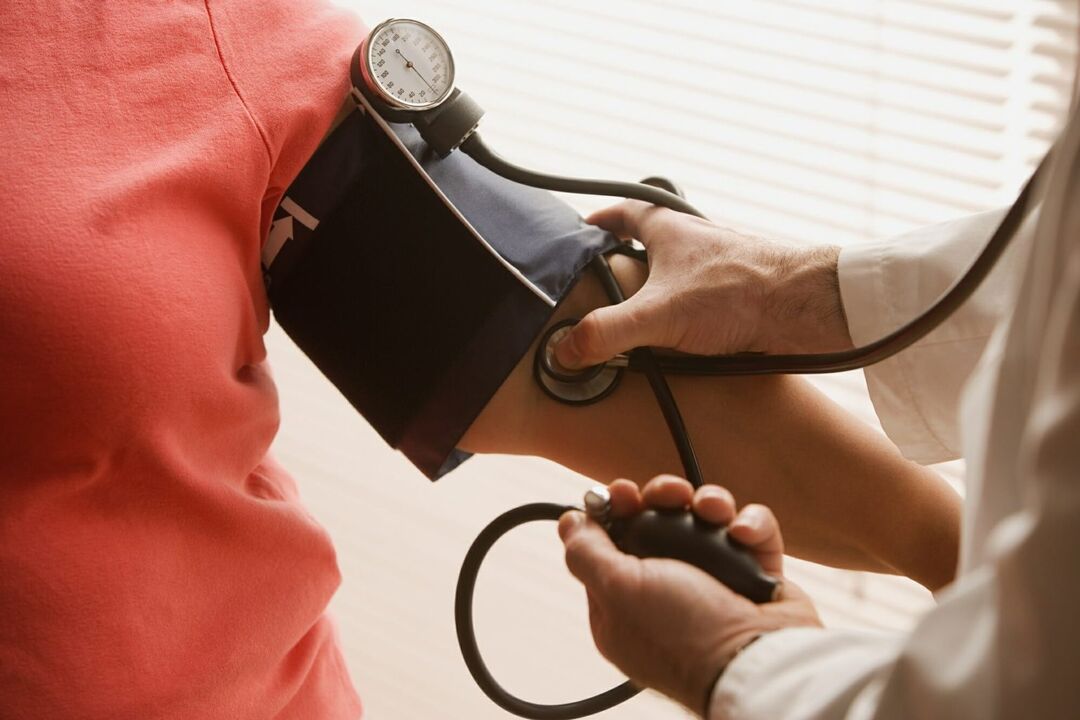 Médico medindo a pressão arterial de um paciente com hipertensão